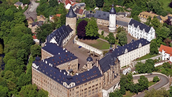 Luftbild einer weitläufigen von viel Grün umgebenen Schlossanlage mit zwei markanten Türmen
