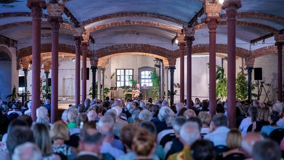 Publikum von hinten mit Blick auf lesenden Schauspieler Thomas Thieme bei der Veranstaltung im Konzertstall in Seggerde