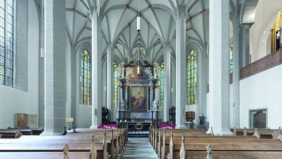 Blick in den Dom St. Petri Bautzen, helle gotische Säulen, vor dem Altar hölzerne Kirchenbänke. 