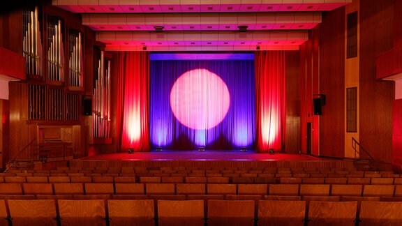 Der Saal im Kulturhaus in Gotha: Blick über leere Stuhlreihen zur Bühne, auf dem geschlossenen Vorhang ist der Kreis eines Scheinwerfers zu sehen.