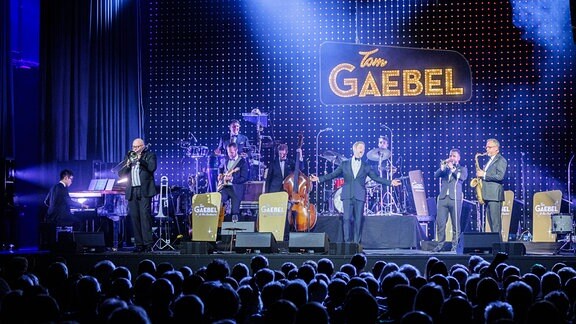 Sänger und Entertainer Tom Gaebel mit seiner Band auf der Bühne vor viel Publikum beim MDR-Musiksommer in der Festhalle Ilmenau