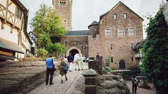 Konzertgäste laufen Richtung Hauptgebäude auf dem Gelände der Wartburg.