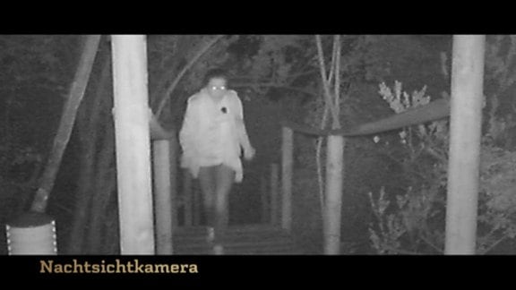 Mit Nachtsichtkamera aufgenommenes Bild einer Frau, die über einen Steg läuft