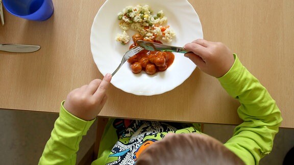 Ein Kind isst ein warmes Essen in der Kita