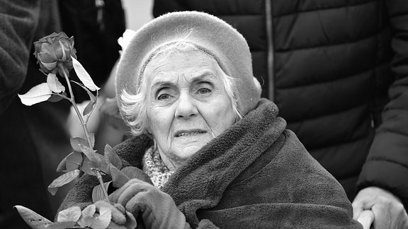 Die Buchenwald-Überlebende Eva Fahidi-Pusztai hält bei einer Gedenkveranstaltung zum 74. Jahrestag der Befreiung des früheren KZ Buchenwald auf dem ehemaligen Appellplatz eine Rose in der Hand.