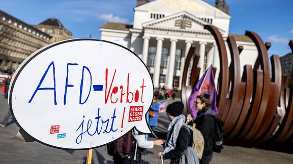 Vor dem Stadttheater zeigt ein Teilnehmer ein Schild mit der Aufschrift "AFD-Verbot jetzt".