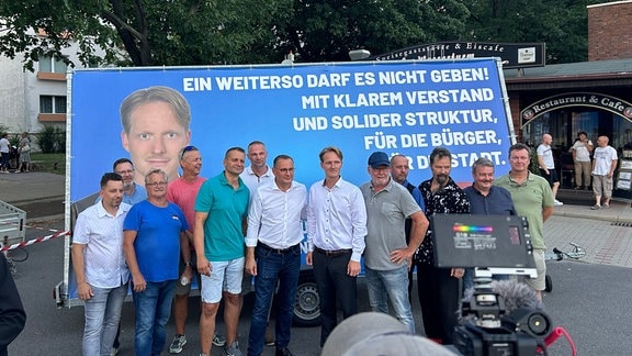 Personen stehen vor einem Plakat