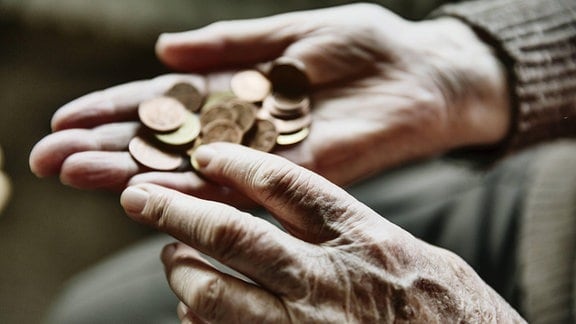 Seniorin zählt Münzen in ihrer Hand.