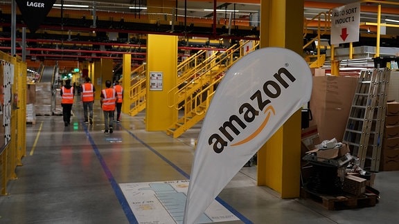 Mitarbeiter in der Werkhalle mit Amazon Logo