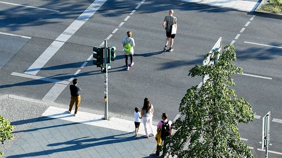 Fußgänger an einer Fußgängerampel; während einige Passanten auf grün warten, überqueren andere bereits die Straße