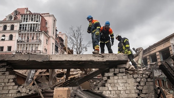 Rettungskräfte auf einem zerstörten Gebäude in Charkiw