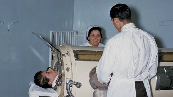 Mediziner neben Patient in Eiserner Lunge
