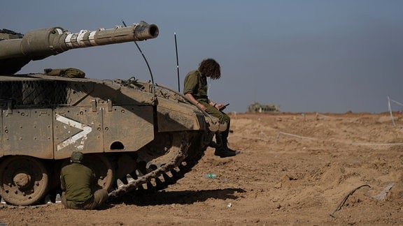 Ein israelischer Soldat sitzt auf einem Panzer und schaut auf ein Smartphone, nach Inkrafttreten einer vorübergehenden Feuerpause zwischen Israel und der islamistischen Hamas.