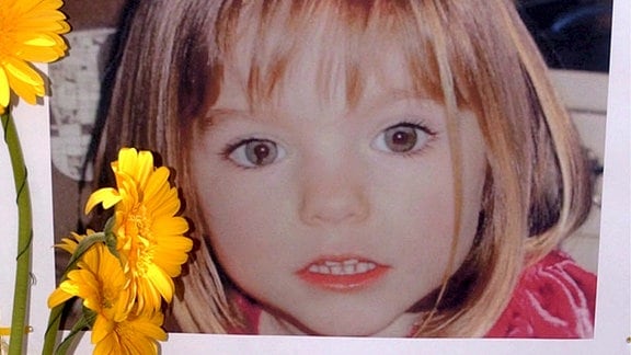 Blumen stehen 2007 vor einem Bild der verschwundenen Madeleine McCann.