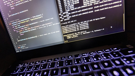  Quellcode eines Webservers sowie die Windows-Eingabeaufforderung sind einem Laptop im Dunkeln zu sehen.