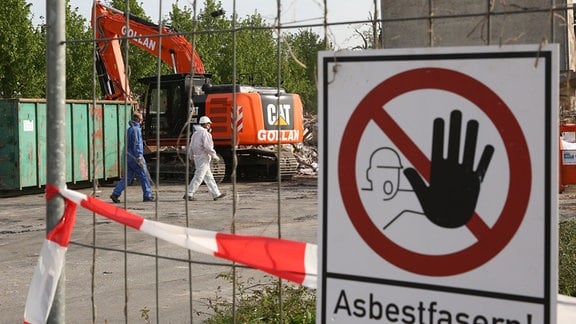 Auf einem Sammelplatz, wo der asbestbelastete Schutt lagert, warnt ein Schild "Asbestfasern!".