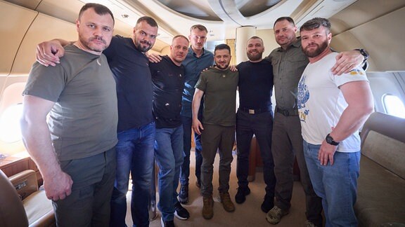 Wolodymyr Selenskyj und weitere Männer nebeneinander in einem Flugzeug
