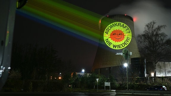Aktivisten der Anti-Atom-Bewegung projizieren eine große Anti-Atom-Sonne auf den Kühlturm eines Atomkraftwerkes