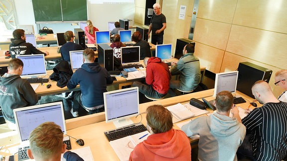 Auszubildende sitzen in einem Computerkabinett vor Rechnern