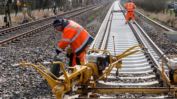 Bahnarbeiter verlegen Gleise auf ausgetauschten Schienen