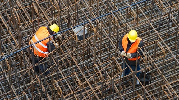 Bauarbeiter errichten auf einer Baustelle ein Stahlgeflecht