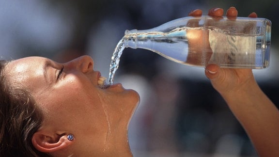 Frau trinkt Mineralwasser aus Flasche bei großer Hitze