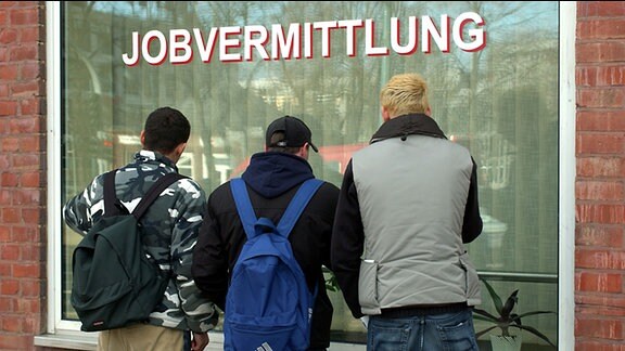 Drei Jugendliche stehen vor dem Fenster einer Job-Agentur