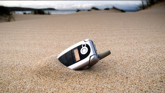 Ein Handy steckt Sand