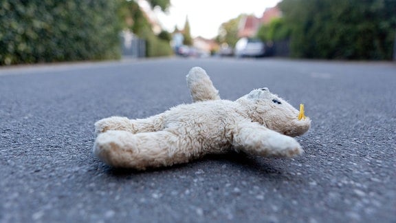 Ein Teddybär liegt auf einer Straße.