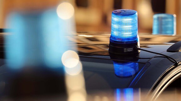 Eingeschaltetes Blaulicht auf dem Dach eines zivilen Polizeifahrzeuges spiegelt sich auf der Frontscheibe.