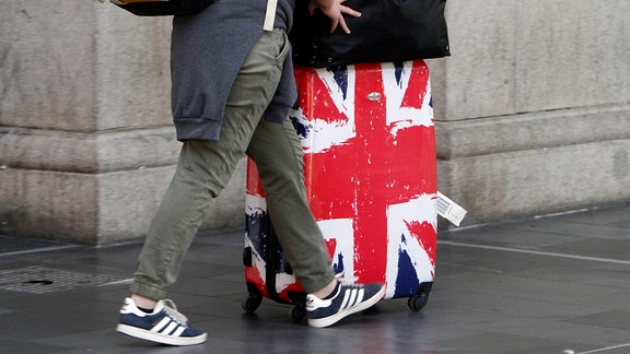 Bahnreisende mit einem Rollkoffer in den Farben der Flagge Großbrittaniens