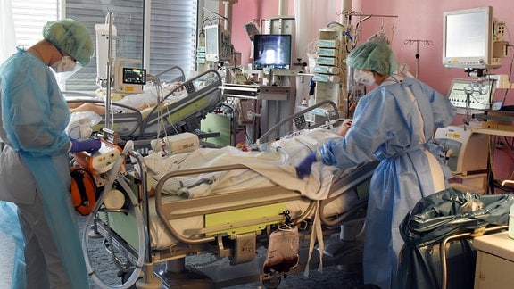 Auf der Covid-19-Station, einem Bereich der Operativen Intensivstation vom Universitätsklinikum Leipzig, bereiten eine Ãrztin (l) und eine Schwester einen Patienten für eine Untersuchung vor.