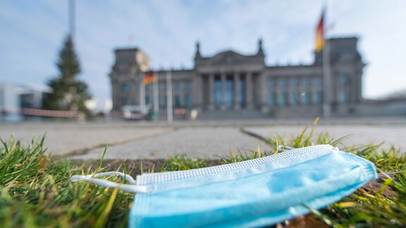 Ein Mund-Nasen-Schutz liegt auf der Wiese vor dem Deutschen Bundestag Berlin.