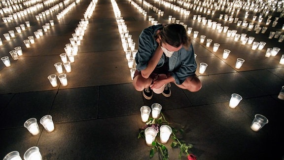 Ein Mann sitzt inmitten von Kerzen auf der Prager Burg in Gedenken an die Opfer der Corona-Pandemie