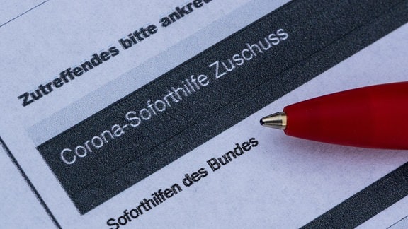 Ein Stift liegt auf einem Antrag für den Corona-Soforthilfe-Zuschuss. 