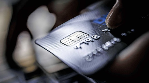 Eine Kreditkarte vom Typ VISA Card wird neben einer Computertatstatur gehalten.