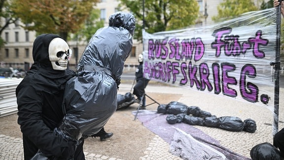 Ein als Tod verkleideter Demonstrant trägt einen symbolischen Leichensack