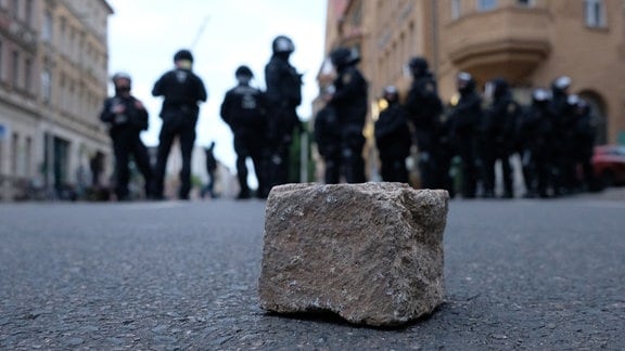 Polizisten stehen auf einer Straße im Stadtteil Connewitz, auf der Pflastersteine liegen