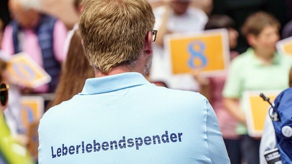 Ein Mann steht am «Tag der Organspende» bei einer Aktion in der Mainzer Innenstadt mit einem T-Shirt mit der Aufschrift «Leberlebendspender».