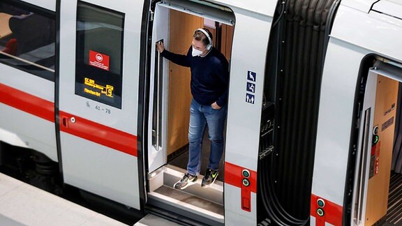 Ein Fahrgast mit FFP2 Maske steht am Berliner Bahnhof steht im Eingang eines ICE Zuges.