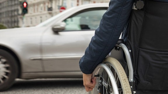 Eine Frau im Rollstuhl wartet an einer Ampel