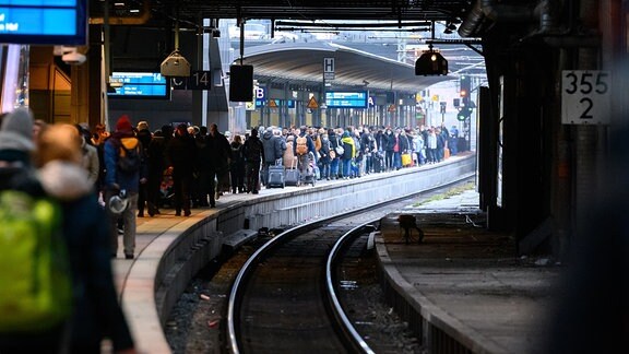 Zahlreiche Fahrgäste warten an einem Bahnsteig