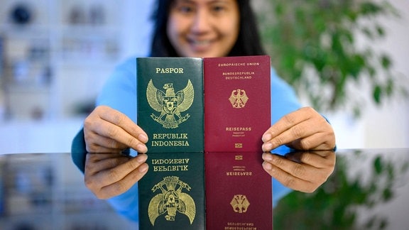 Eine Frau hält einen indonesischen und einen deutschen Pass.