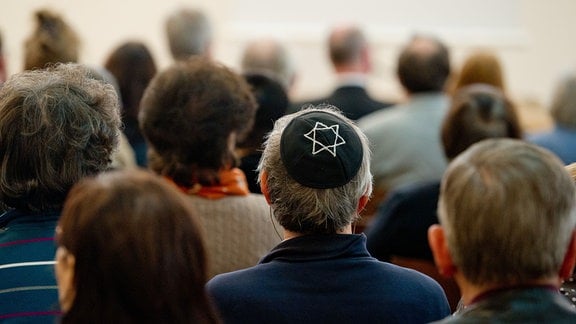 Ein Mann mit einer Kippa sitzt in einer Synagoge.