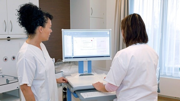 Zwei Krankenschwestern stehen am Monitor und schauen auf eine digitale Patientenakte.
