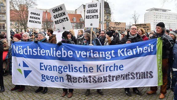 Demonstranten mit einem Banner "Nächstenliebe verlangt Klarheit Evangelische Kirche gegen Rechtsextremismus" und "Omas gegen rechts" demonstrieren gegen die Wahl Kemmerichs zum Ministerpräsidenten von Thüringen. 