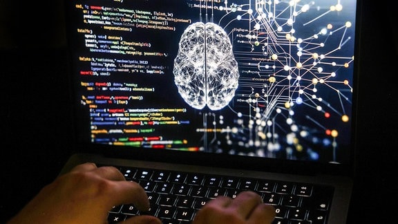 Eine Person arbeitet am Rechner, auf dessen Bildschirm ein durch Künstliche Intelligenz generiertes Illustrationsbild mit Code verschiedener Programmiersprachen und einem neuronalen Netzwerk-Diagramm zu sehen ist.