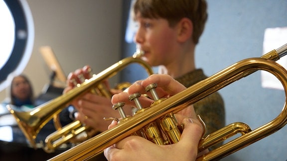 Nahaufnahme zweier Schüler*innen die Trompete spielen.