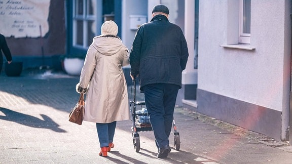 Seniorin und Senior vgehen eine Straße entlang.