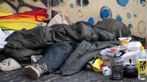 Eine Person liegt in der Innenstadt unter einem Schlafsack